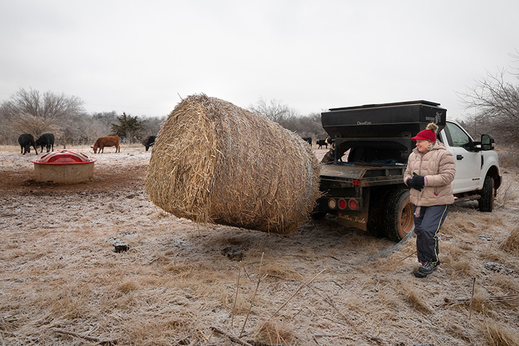 Photo of Marka Acton unloading a hay bale.