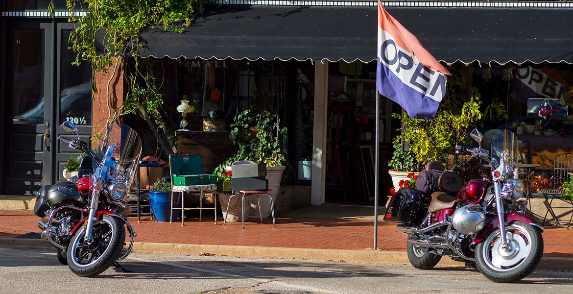 Photo of main street business with big open flag out front.