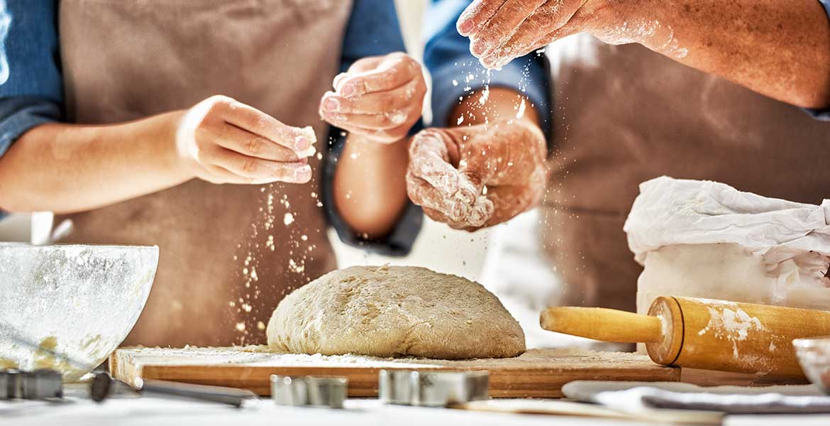 bakers sprinkling flour on dough