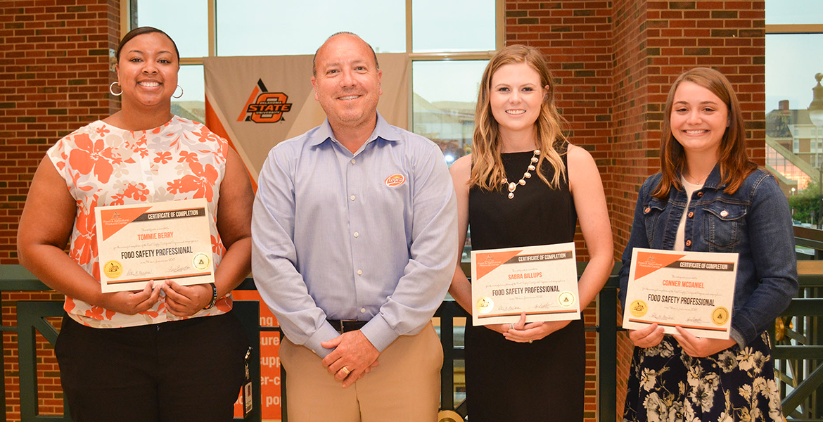 John Lopez of Lopez Foods and chair of FAPC’s Industry Advisory Committee presents Tommie Berry of QuickTrip and Sabra Billups and Conner McDaniel, OSU graduate students, with certificates for completing the Food Safety Professional program.