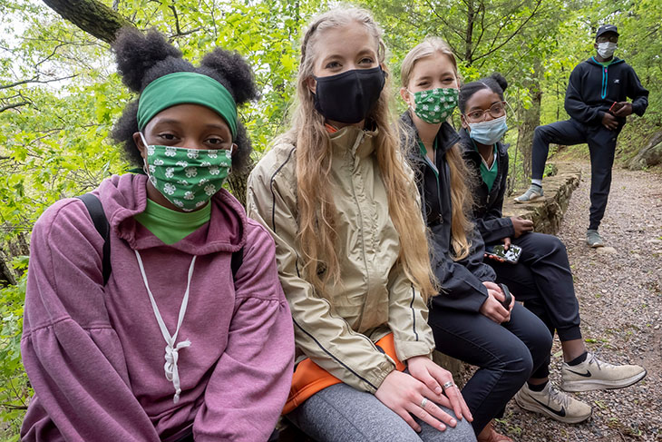 Photo of masked 4-H'ers (following pandemic guidelines) pausing for a rest along a woodlands trail.