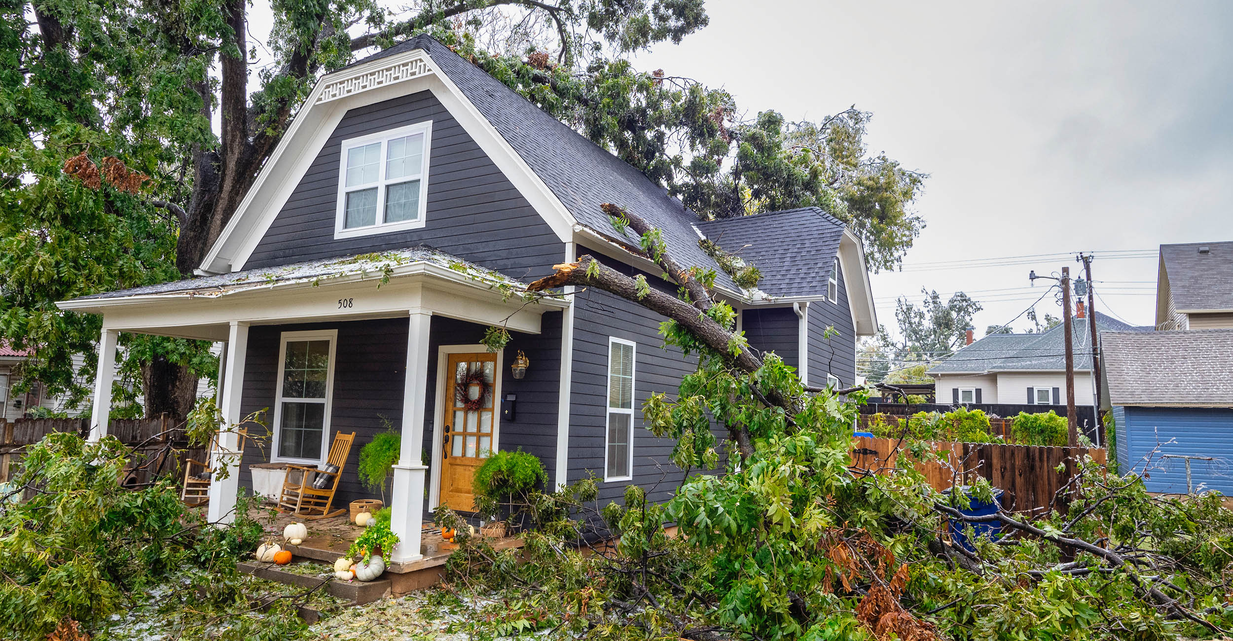 Photo of a house surrounded by tree damage.