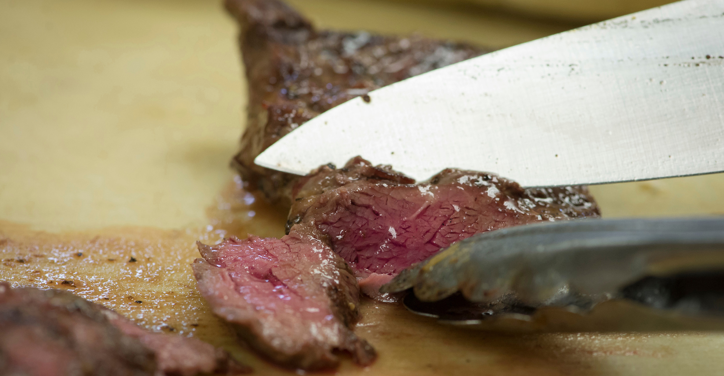 Close-up photo of a knife cutting through a juicy steak.