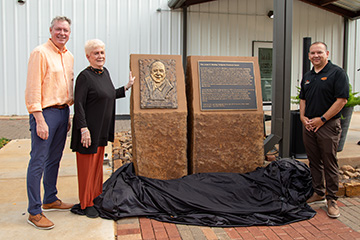 Jayson Lusk, Lou Bentley and Justin Quetone Moss stand next to a sculpture of Lionel K. Bentley at the Lionel K. Bentley Turfgrass Center.