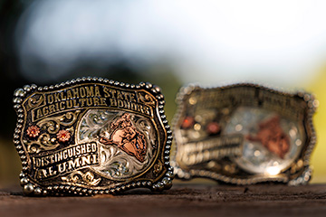 OSU Agriculture Distinguished Alumni custom-made buckle displayed on a wooden surface.