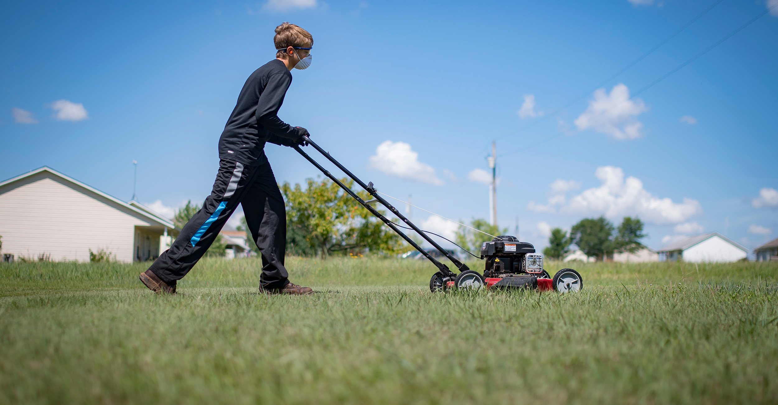 Boy mowing the yard.