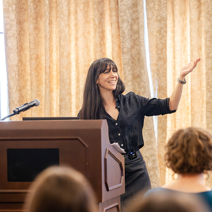 A speaker gestures from behind a podium while addressing an audience during the Humanities Week keynote lecture in the Helmerich Browsing Room.