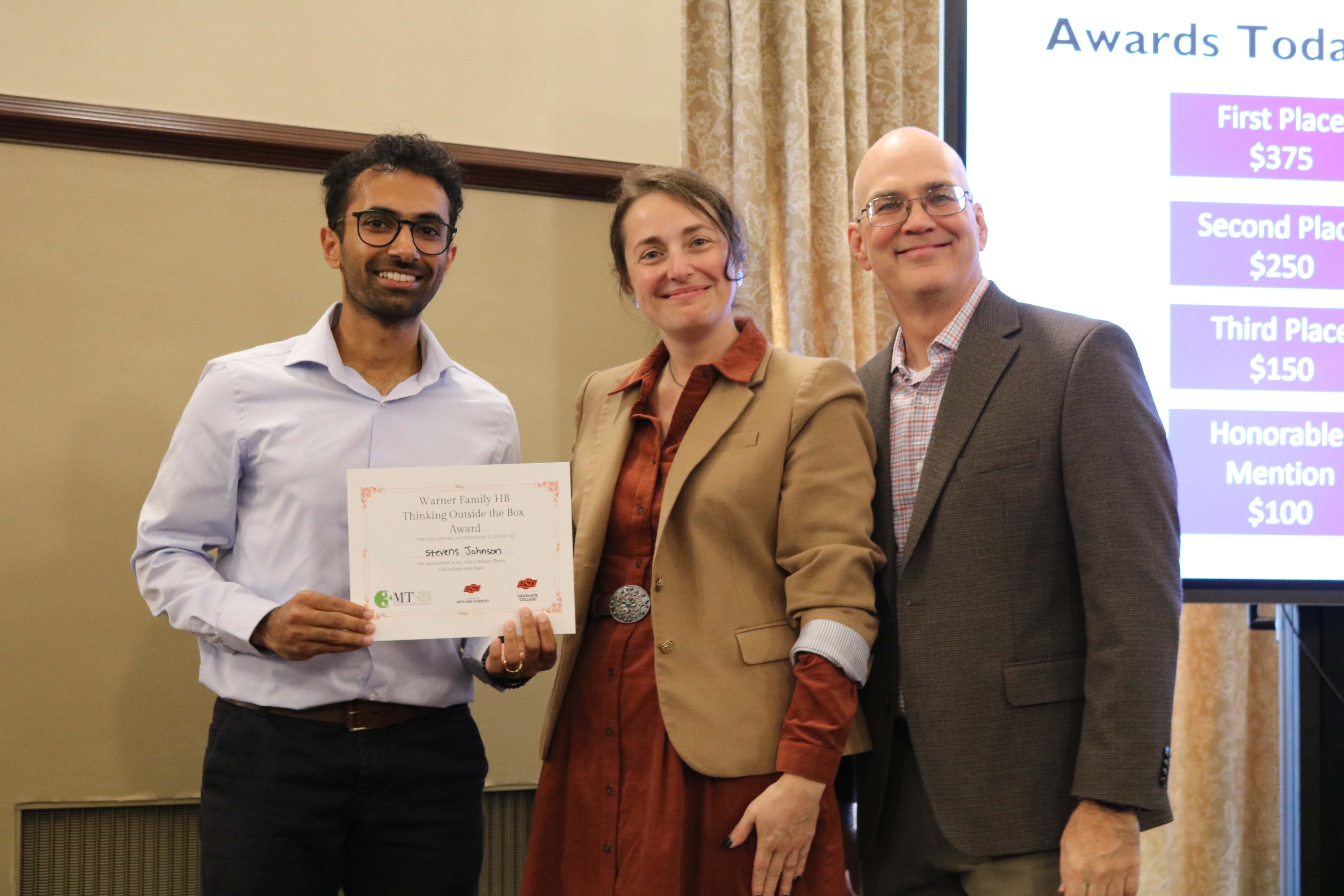 Thinking outside the box winner in the 2026 College of Arts and Sciences Three Minute Thesis competition, Stevens Johnson, with Dean Melinda Cro and Associate Dean for Research Jason Belden.