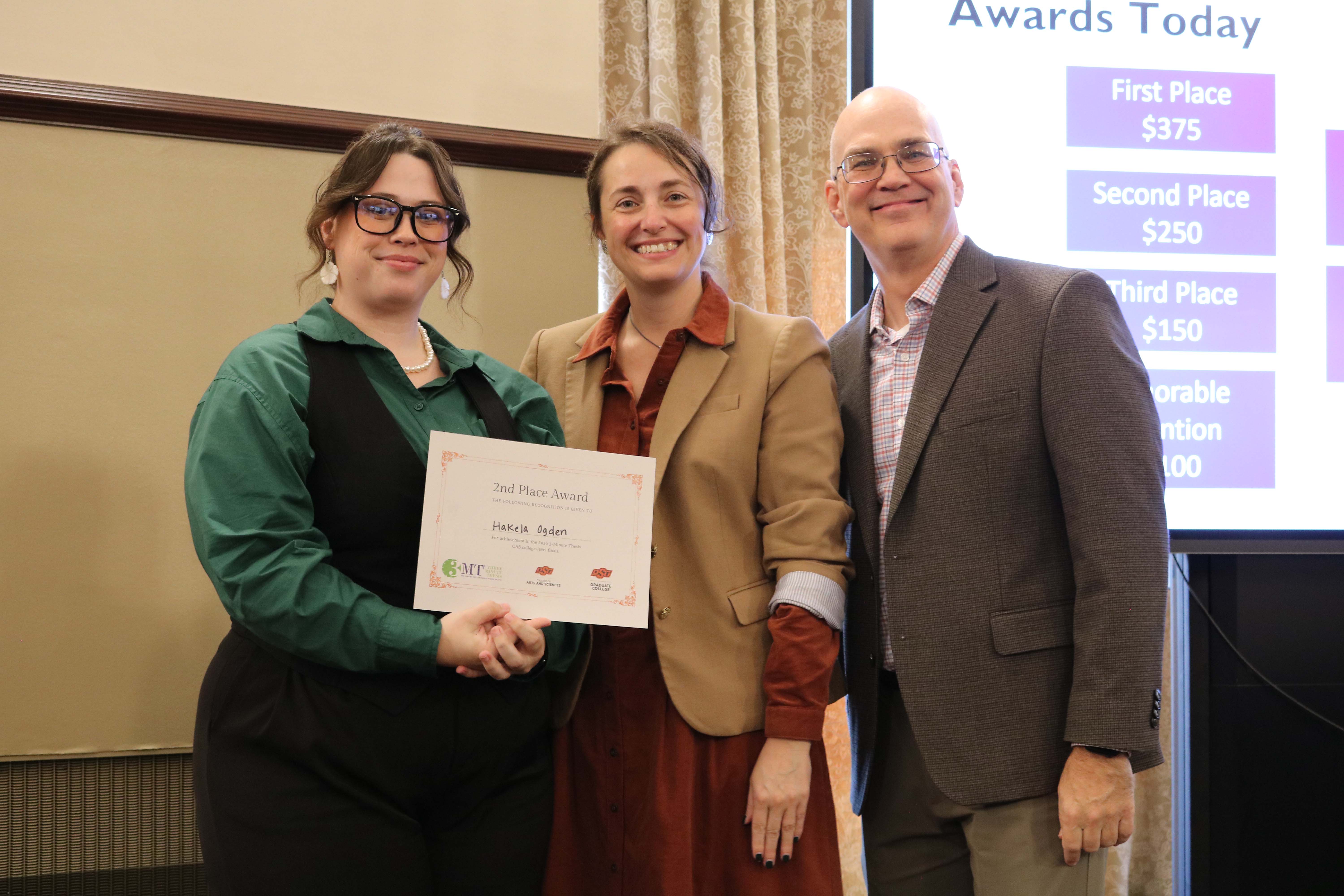 Second place in the 2026 College of Arts and Sciences Three Minute Thesis competition, Hakelaho‘imaiokalani Ogden, with Dean Melinda Cro and Associate Dean for Research Jason Belden.
