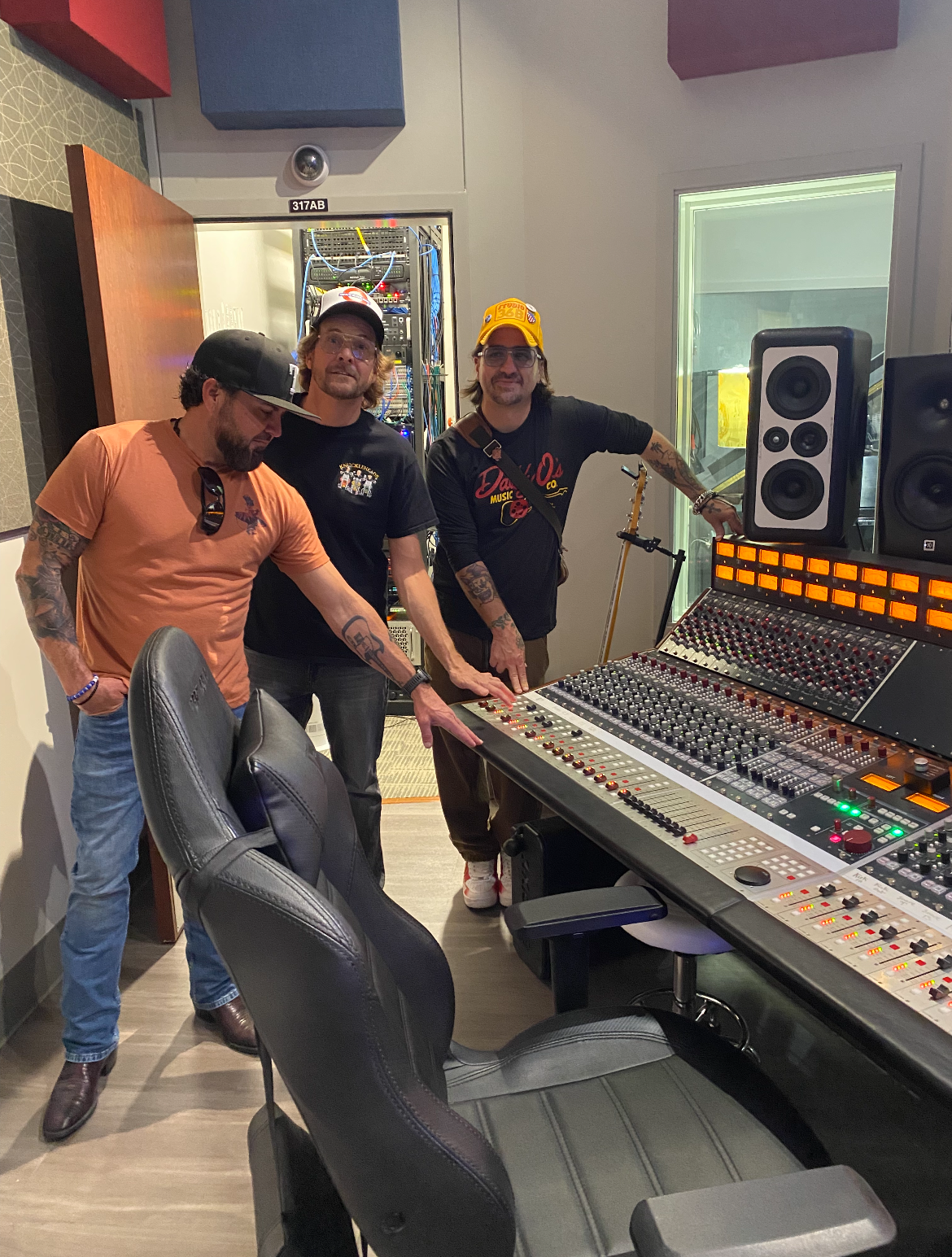 Three members of Cross Canadian Ragweed stand around a mixing console in a recording studio.