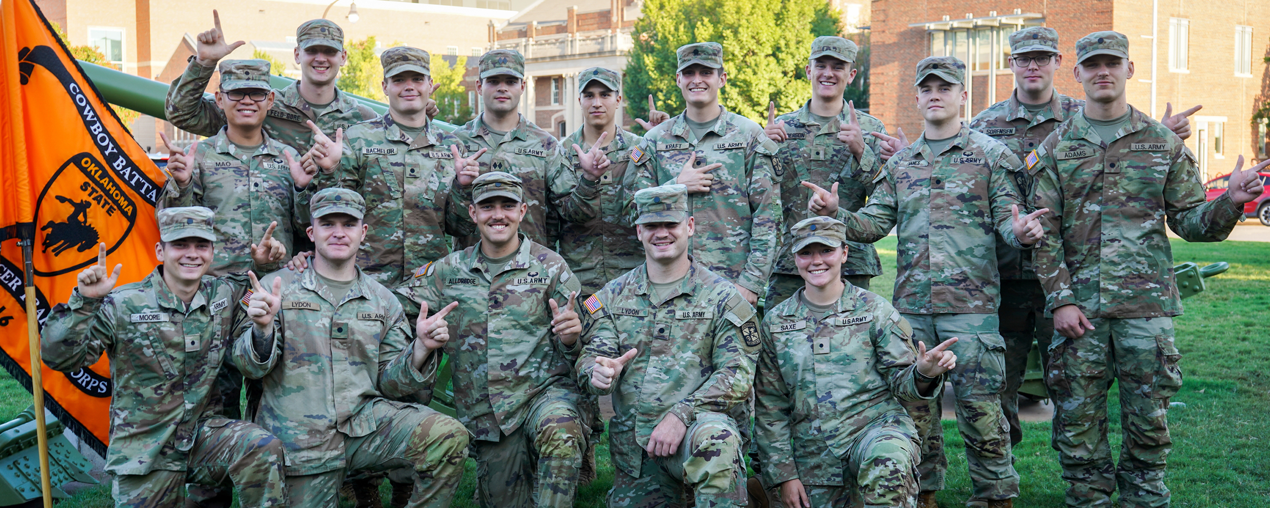 OSU Army ROTC cadets pose together in uniform with the Cowboy Battalion flag.
