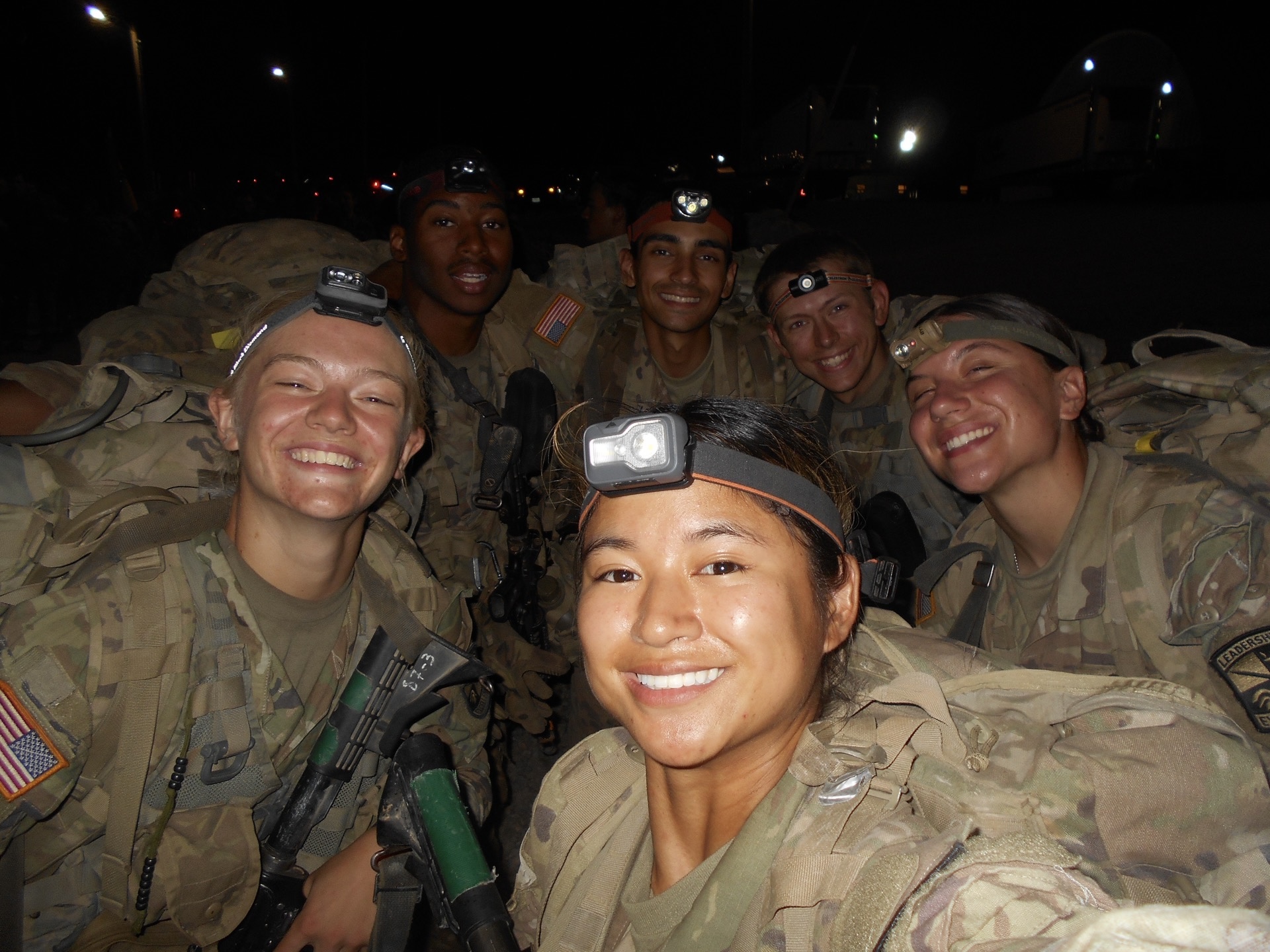 Lucy Stuteville and five fellow cadets wearing headlamps smile for a nighttime group photo.