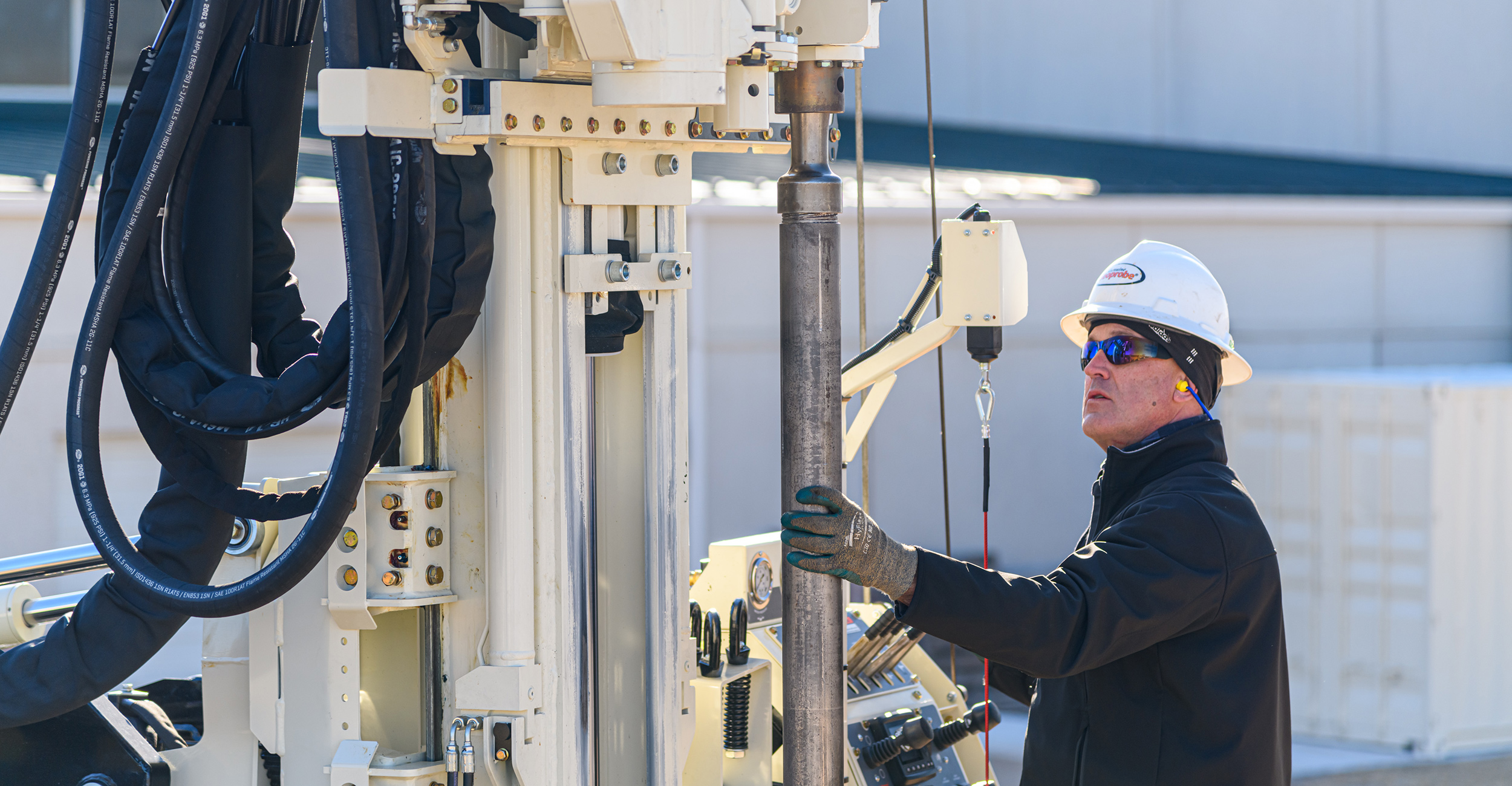 A male groundwater professional operates a drilling rig in the field.