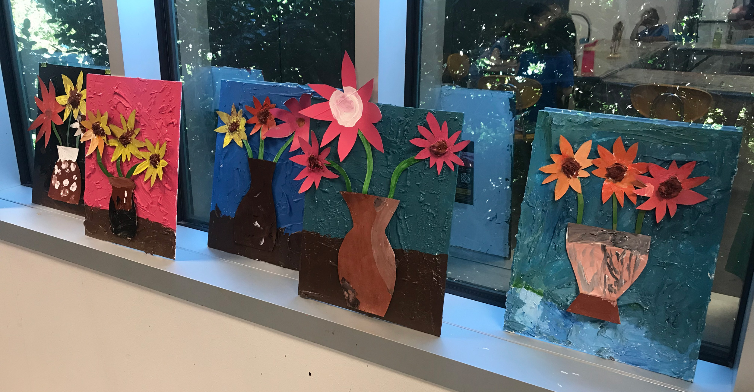 Children's artwork of potted flowers made out of paper and paint.