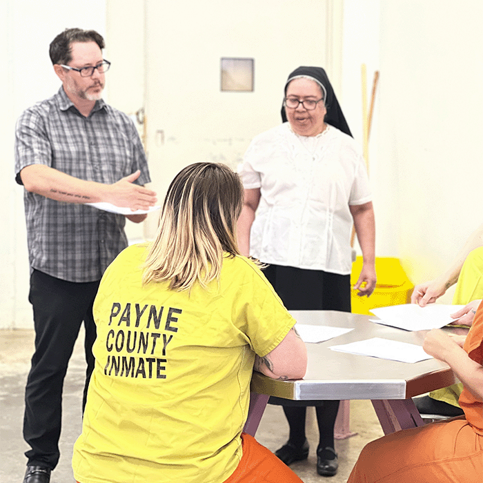 Dr. Eric Howerton and Sister Catherine Martinez work with inmates on class work.