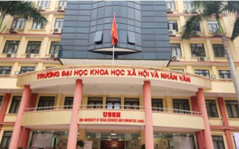 The front entrance of the University of Social Sciences and Humanities in Hanoi is shown, featuring a multi‑story academic building with Vietnamese signage and a national flag above the main doorway.