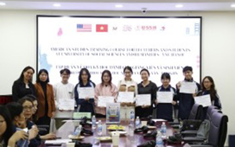 A group of participants stands together holding certificates in front of a banner for an American Studies training course at the University of Social Sciences and Humanities in Hanoi, marking the completion of an academic program.