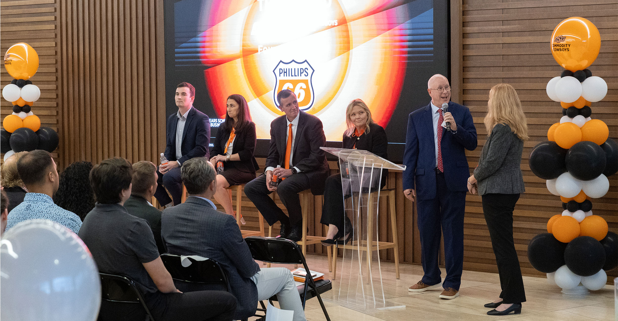 A panel of executives speak to a crowd about a new program at Spears School of Business.