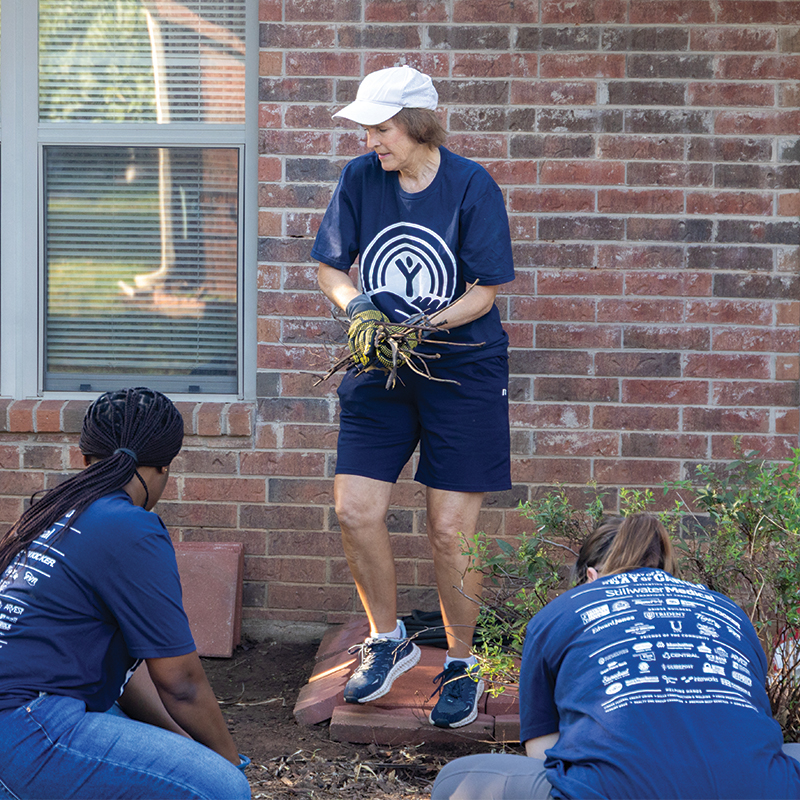 Dr. Julie Weathers cleans up a flower bed during the United Way Day of Caring in Stillwater