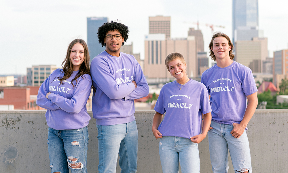 Miracle Group Four people wear matching In the Middle of a Miracle shirts.