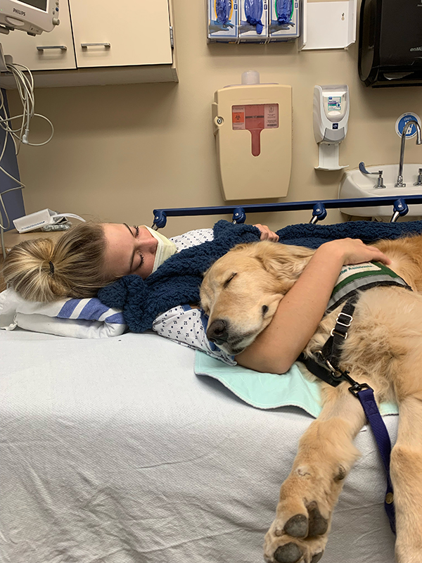 Brooklyn hospital a girl cuddles with a dog in a hospital bed