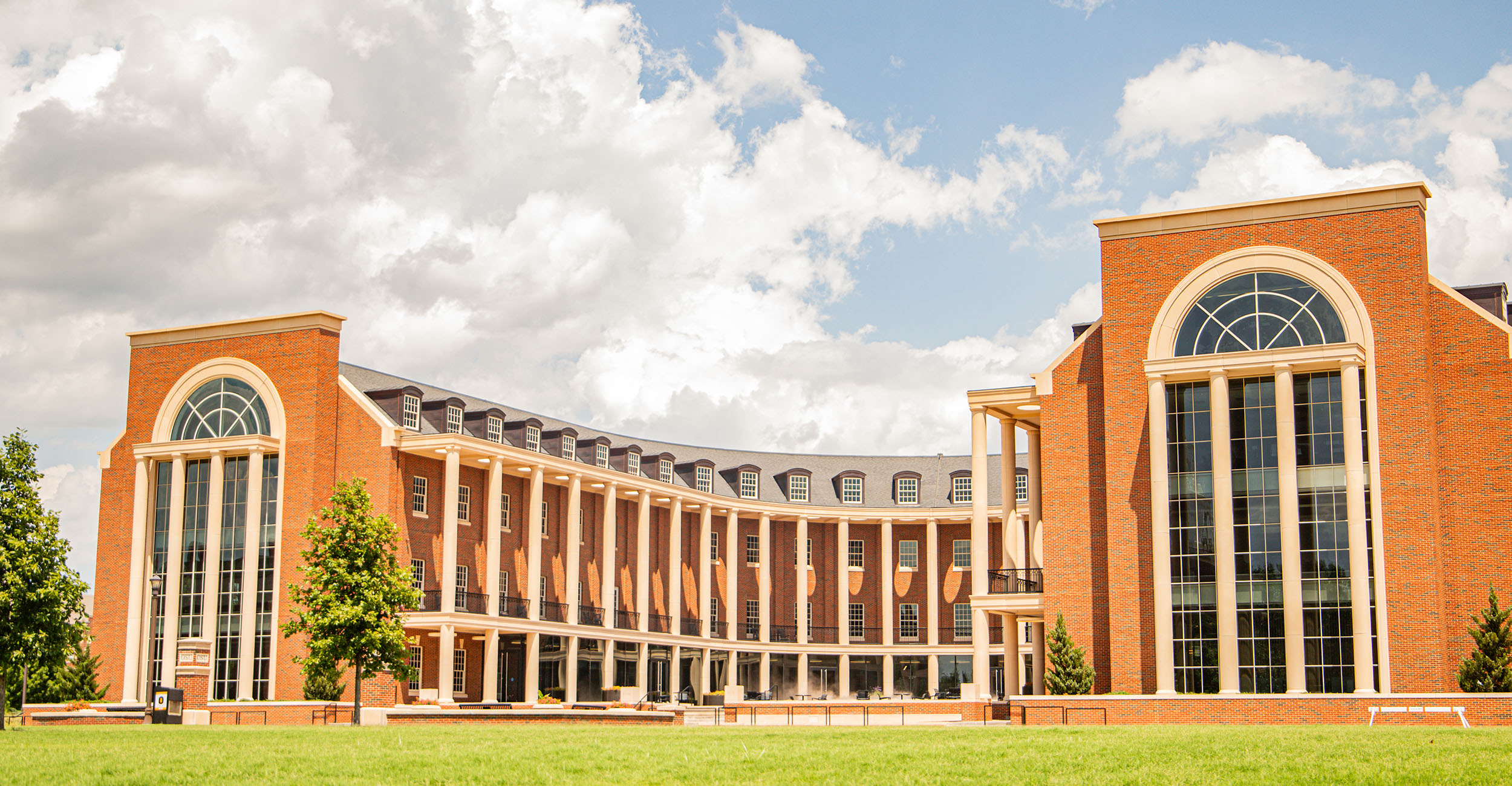 The Business Building at Oklahoma State University from the West, with the signature crescent shape showing. There is a beautiful blue sky above the building.