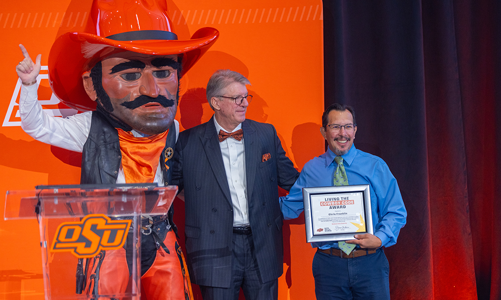 Chris Franklin accepts his award from President Hess with Pistol Pete on stage.
