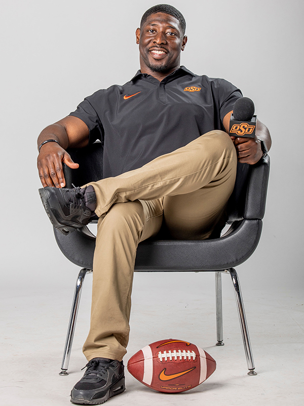 Deion Imade seated with a microphone and a football