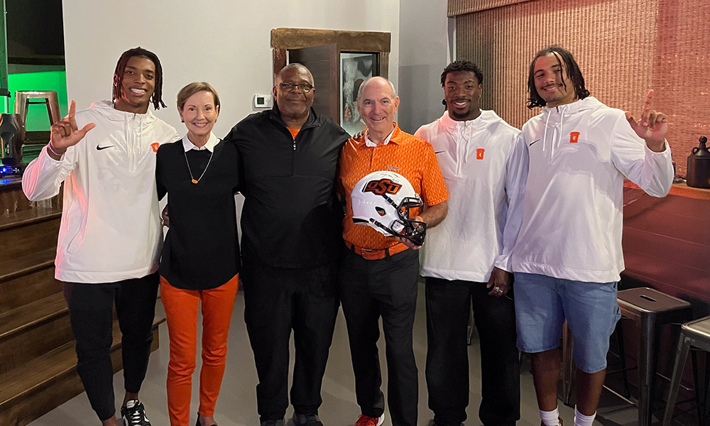 Eddy and Deniece Ditzler pose with Cowboy football legend Terry Miller as well as current Cowboy football players.