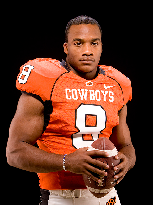 Donovan Woods wears his orange Cowboy football jersey and holds a football.