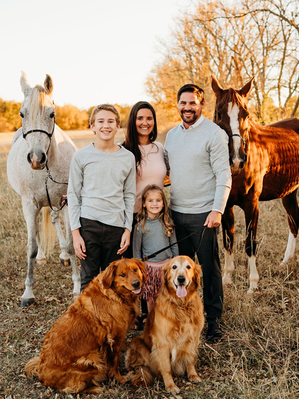 The Elwell family poses for a portrait with two dogs and two horses.