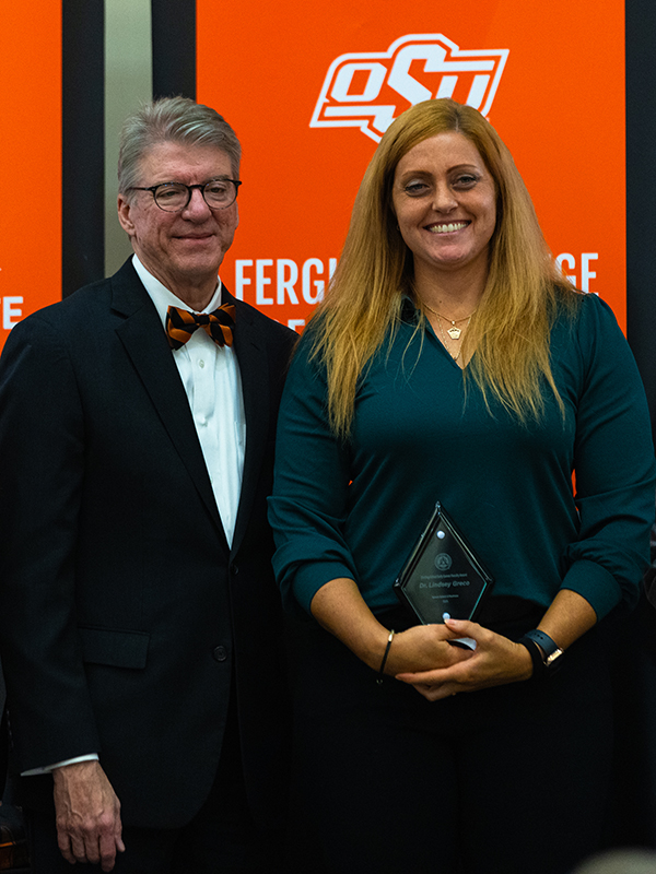 Dr. Lindsey Greco Dr. Lindsey Greco, wearing a dark green top, accepts an award next to OSU president Jim Hess.