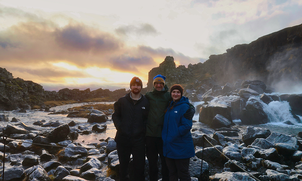 Joseph, Neil and Emily Hansen with rocks and cliffs behind them