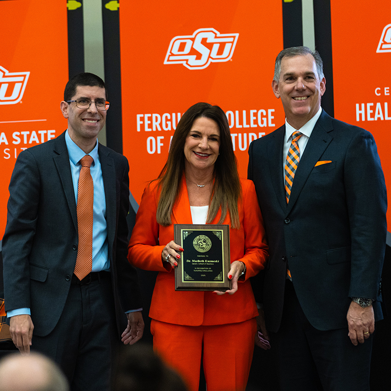 Maribeth Kuzmeski Dr. Maribeth Kuzmeski, a woman in an orange pantsuit, accepts her award.