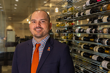 Kyle Bunds portrait in a suit and orange tie in the wine cellar of Taylor's Restaurant.