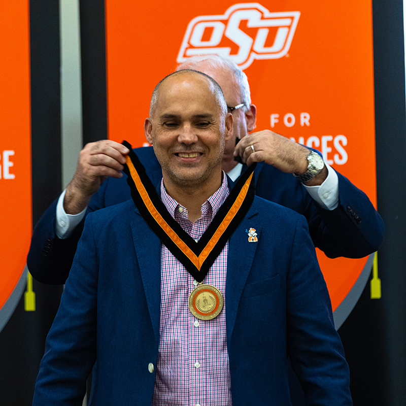 Dr. Rick Laux Dr. Rick Laux, a man in a navy sport coat, accepts his medlalion from Dean Jim Payne.