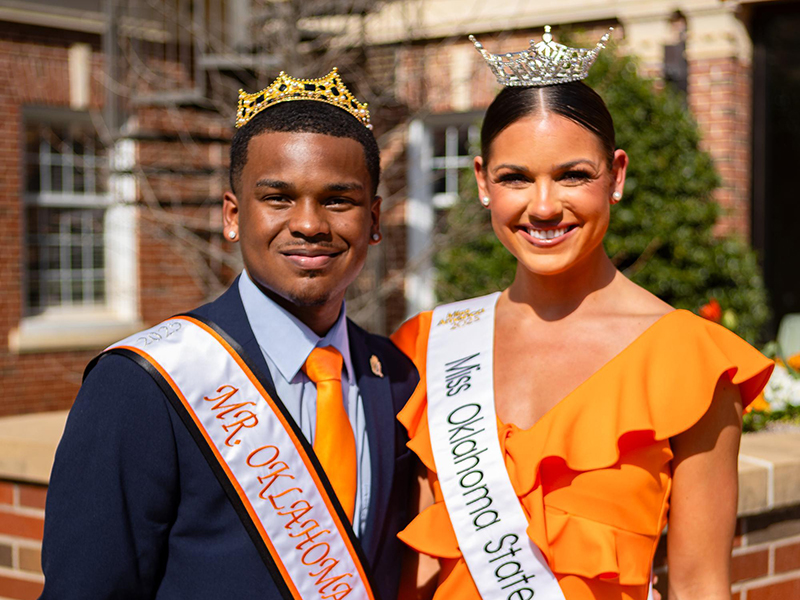 Mr. OSU and Miss OSU stand side by side, each wearing a crown and sash.