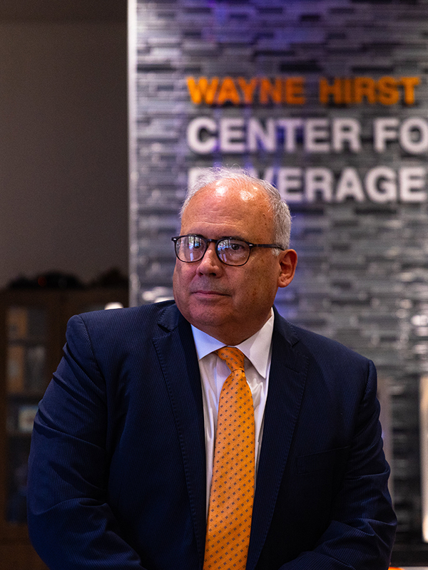 Dr. Jim Payne, Dean of Spears Business, wearing a blue suit with an orange tie.