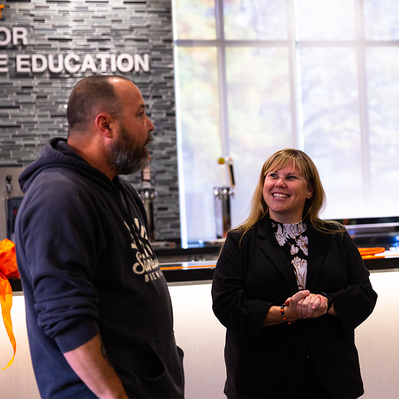 Ashley Peterson smiling while chatting with a representative of Stonecloud Brewing.