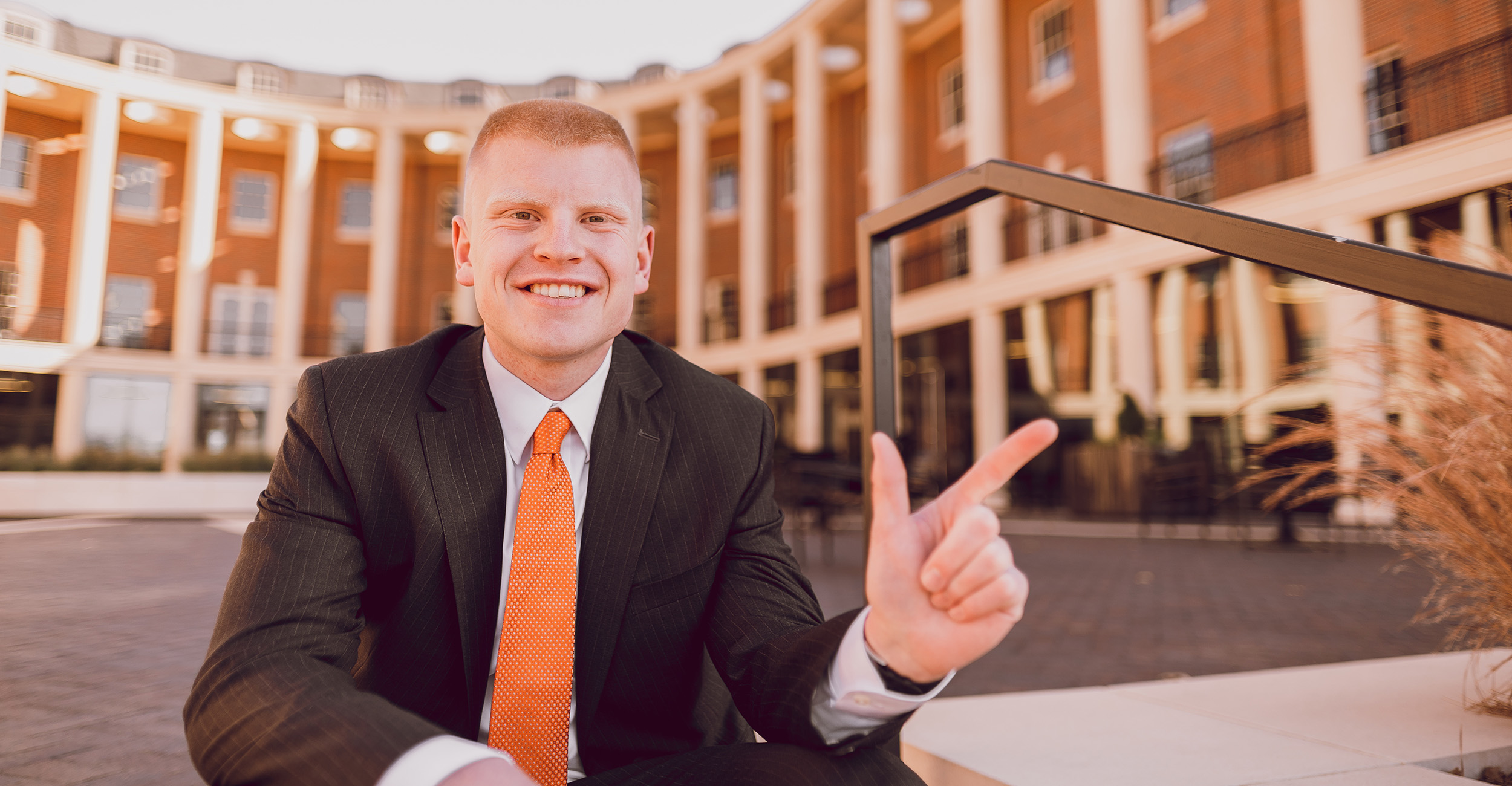 Trey Reeves give the "Go Pokes" hand sign in front of the OSU Business School prior to his graduation in 2021.