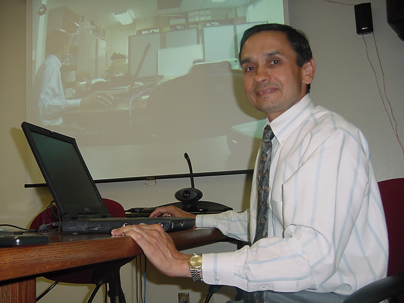 A man sits behind a laptop.