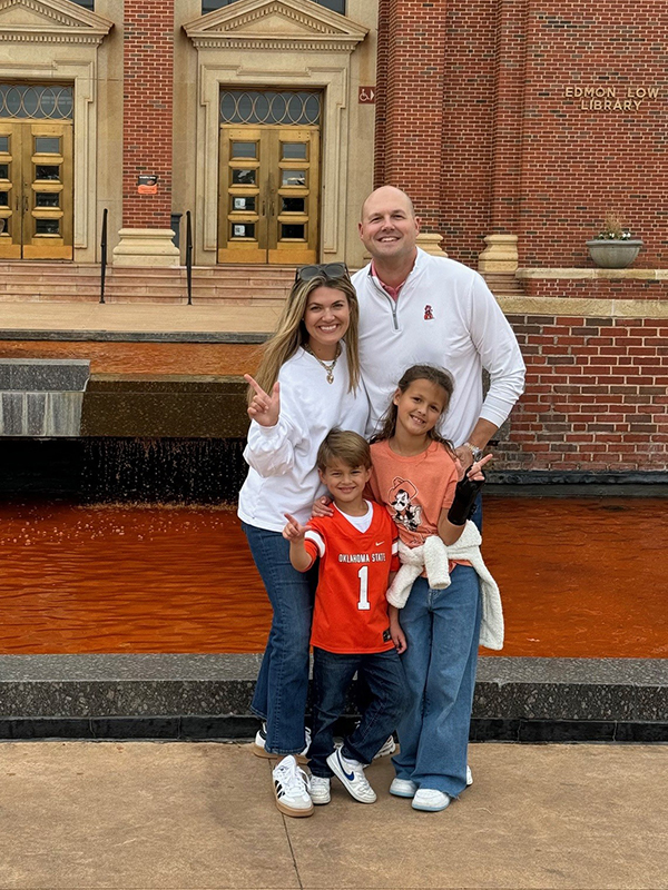 The Sizemore family of four outside Edmon Low Library. The fountain is dyed orange for homecoming.