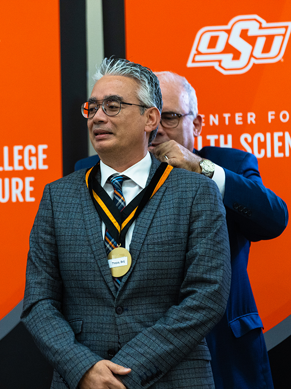 Dr. Thapa Dr. Brij Thapa, a man in a gray suit, accepts his medallion from Dr. Jim Payne.