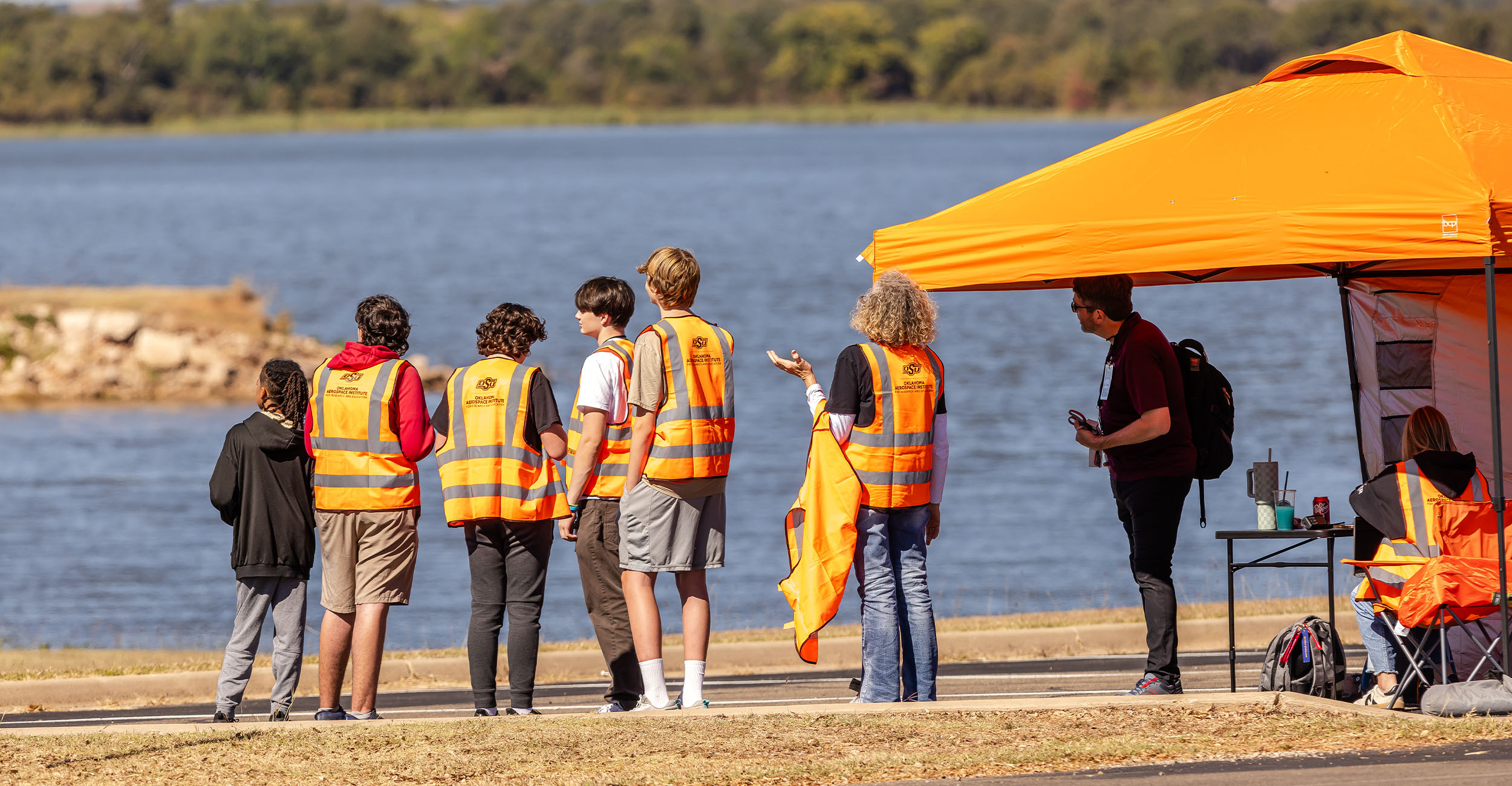 A group of students stare out over a lake during a drone competition near Stillwater.