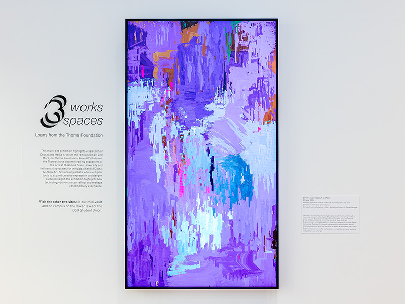 Abstract, vertically oriented artwork mounted on a dark wall, featuring layered, gestural patches of blue, pink, yellow, and green that create a textured, painterly composition.