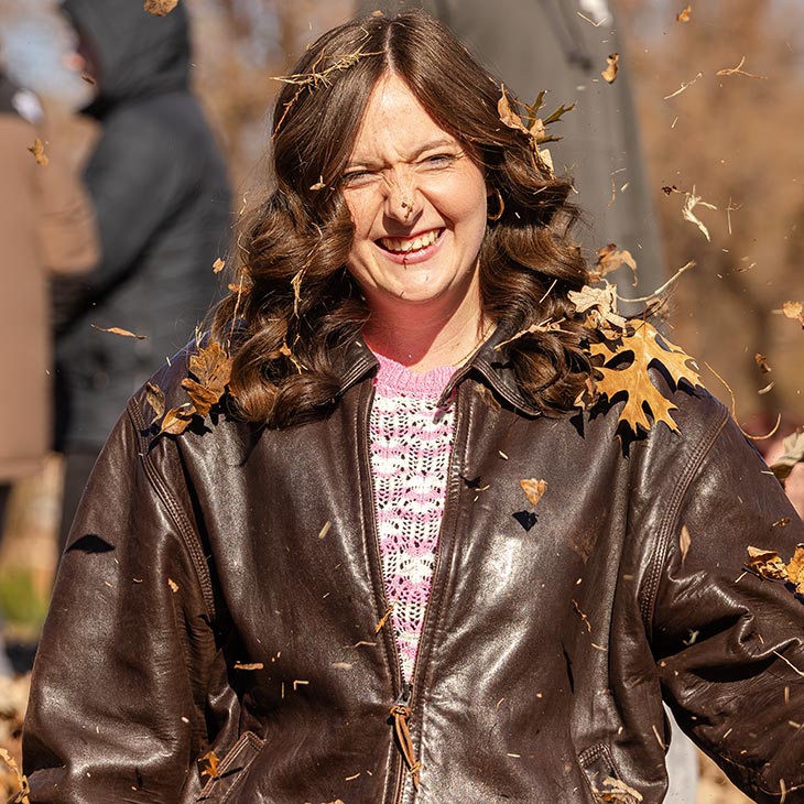 a female college student throws leaves in the air