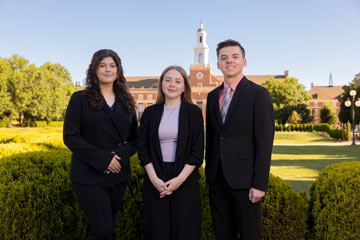 two women and one man stand together wearing suits in front of of the Edmon Low Library