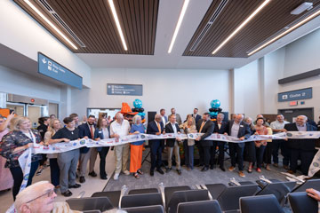 A group of people cut ribbon signifying the grand opening of the new airport terminal.