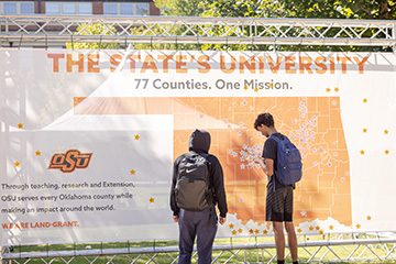 Students add hometown stickers to a large Oklahoma map display during OSU’s Land-grant Week celebration, highlighting the university’s land-grant mission of serving communities across the state’s 77 counties.