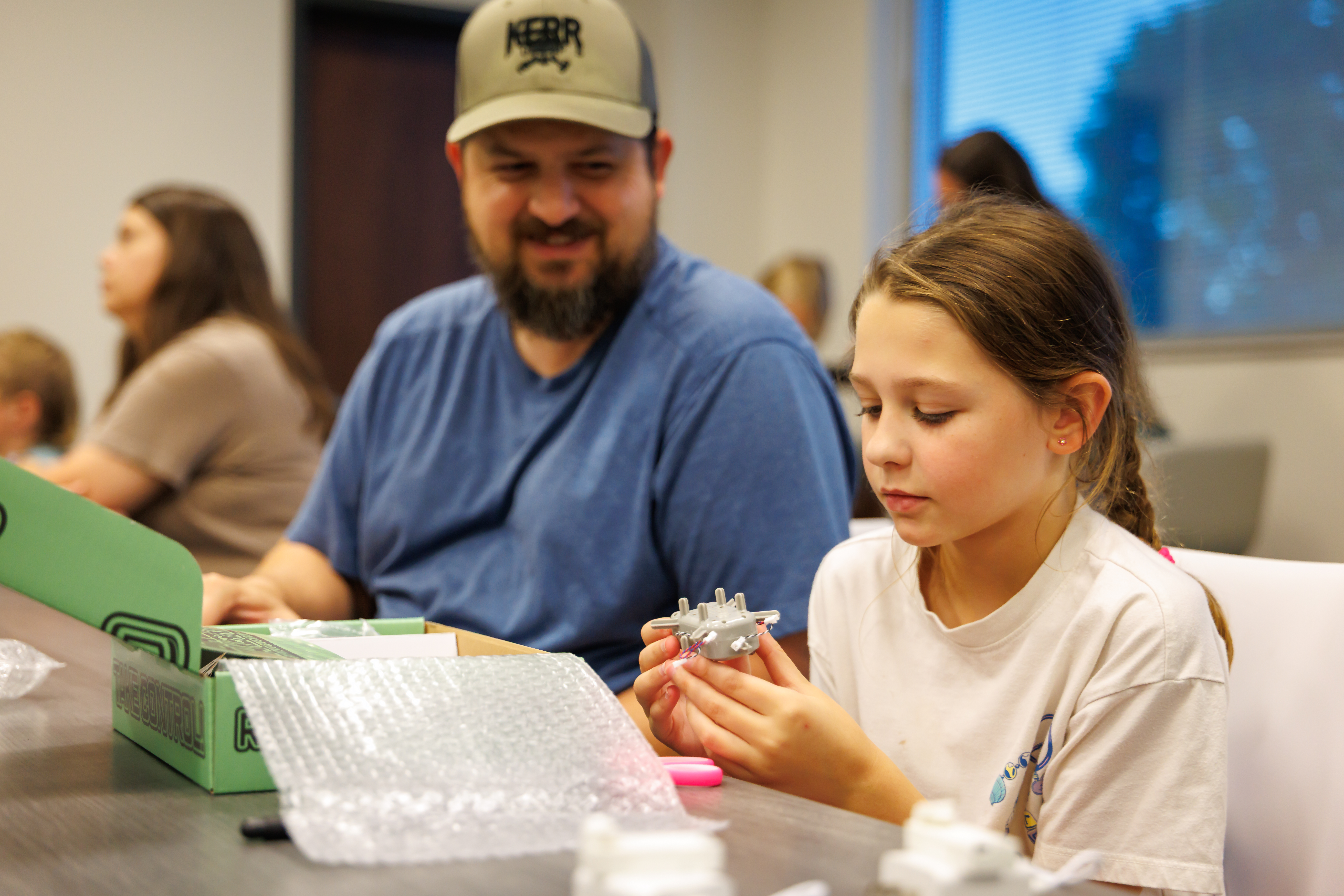 An adult helps an elementary student build a drone. 